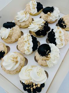 there are many cupcakes with black and white frosting on them in a box