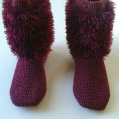 a pair of purple knitted boots sitting on top of a white table