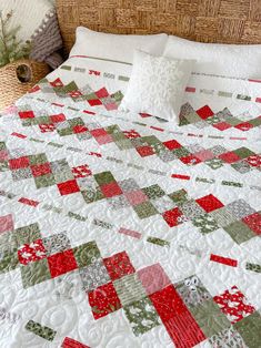 a bed with a white and red quilt on it's headboard next to a wicker basket