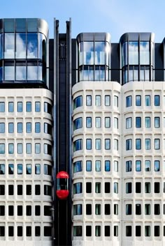 two tall white buildings with windows on each side and a red stop sign in the middle