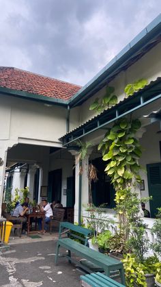 people are sitting at tables in front of a building with plants growing on the roof