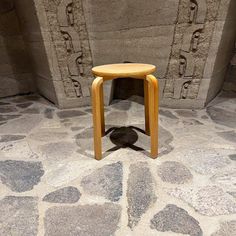 a small wooden stool sitting on top of a stone floor