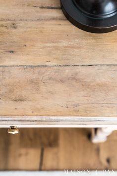 an old wooden table with a black clock on top