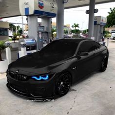 a black car parked in front of a gas station with blue lights on it's hood