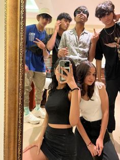 a group of young people taking a selfie in front of a mirror with their reflection