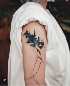 a woman's arm with a watercolor painting on it and trees in the background