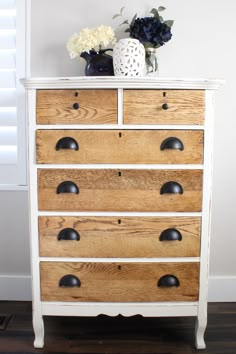 a white dresser with wooden drawers and black knobs