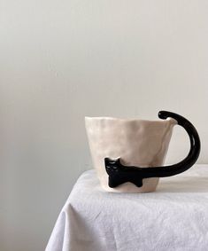 a black and white ceramic cup with a bow on the handle sitting on a table