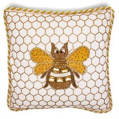 a yellow and white pillow with a bee on it's back, in front of a netted background