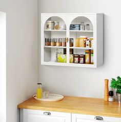 a kitchen with white cabinets and shelves filled with various types of condiments on the wall