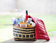 a basket filled with items sitting on top of a wooden table next to a red jacket