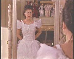 a woman in a white dress looking at herself in the mirror