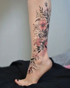 a woman's foot with flowers and leaves on the bottom part of her leg