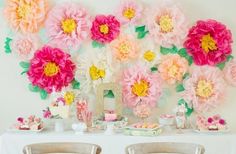 a table topped with lots of pink and yellow flowers on top of it's walls