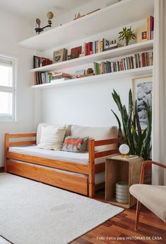 a living room filled with furniture and bookshelves next to a white rug on top of a hard wood floor