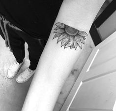 a black and white photo of a sunflower tattoo on the right arm, with an outline of a flower in the middle