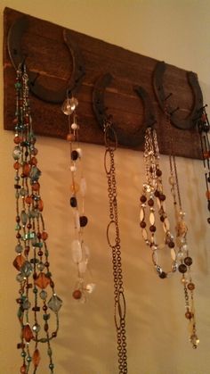 several necklaces are hanging from a wooden hook on the wall in front of a white wall