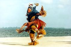 two people dressed in costumes are dancing on the beach