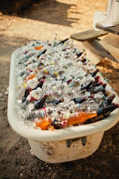 an old bathtub filled with lots of bottles and empty beer bottles sitting on the ground