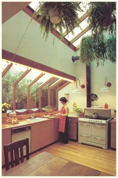 a woman standing in a kitchen next to a stove top oven under a skylight