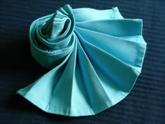 a blue cloth is folded on top of a black surface with the end rolled up