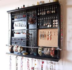 a wall mounted jewelry organizer with lots of earrings