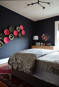 a bed room with a neatly made bed and lots of plates hanging on the wall