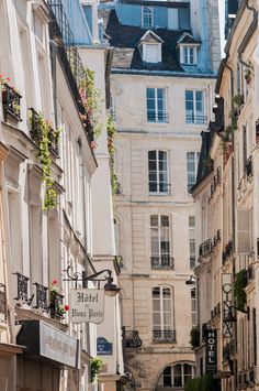 an alleyway in the city with many buildings and people walking down one side, there is a sign that says hotel paris