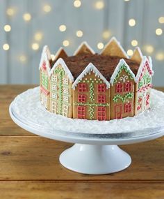 a decorated gingerbread house sits on a cake plate