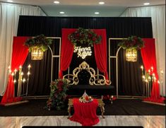 a stage set up with red and black drapes, christmas wreaths, and candles