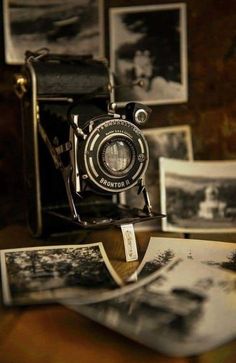 an old fashioned camera sitting on top of a table next to some pictures and photos