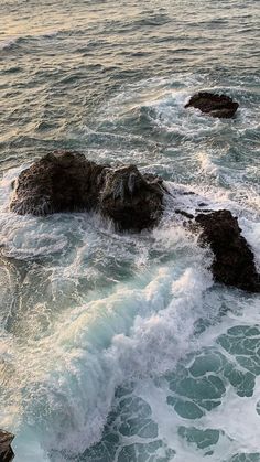 waves crashing on rocks in the ocean at sunset