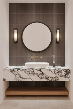 a white sink sitting under a round mirror in a bathroom