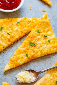 three pieces of cheesy bread on a table with two spoons and ketchup