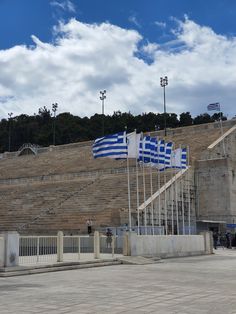 the greek flag is flying in front of an empty stadium bleachers and stairs