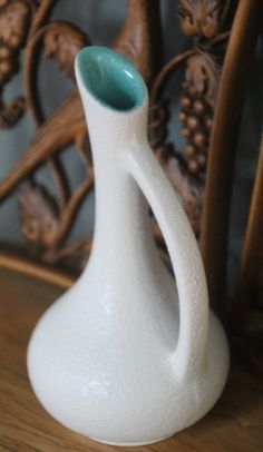 a white vase sitting on top of a wooden table