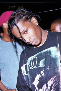 a man with dreadlocks is looking at his cell phone while standing in front of other people