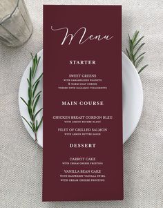 a menu card on top of a white plate next to a fork and knife with rosemary sprigs