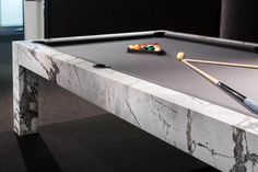 a pool table with two cues and balls on it, in a room that has black walls