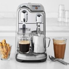 an espresso machine sitting on top of a counter next to a cup of coffee