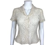 "This is a very attractive blouse made in a cream white cotton machine lace.  The blouse has a high set narrow V neckline with collar, short sleeves and a scalloped edge.  it is unlined, so therefore would require a camisole.  It does up with four mother-of-pearl buttons down the front along with a snap at the bottom. Age: 1940s Label: None Sizing: No size is indicated, and although this should fit a small to medium size, please rely on the following measurements for fit: Shoulders: 16\" across Elegant Short Sleeve Lace Tops, Elegant Short Sleeve Tops With Scalloped Lace, Fitted Scalloped Lace Short Sleeve Blouse, Fitted Scalloped Lace Short Sleeve Top, Short Sleeve Lace Top For Spring Formal, Formal Short Sleeve Lace Top For Spring, Classic Fitted Wedding Blouse, Fitted Short Sleeve Blouse For Formal Occasions, Elegant Short Sleeve Scalloped Lace Top