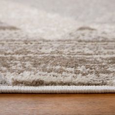 a close up view of a beige and white rug on a wooden floor with wood floors