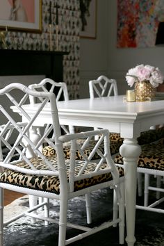 a white table and chairs with leopard print cushions in a dining room area, next to a fireplace