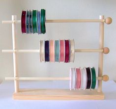 several spools of thread are arranged on a wooden rack with two pegs