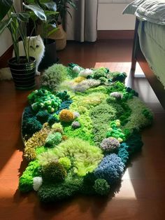 a rug made out of green and blue flowers on the floor next to a bed