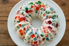 a white plate topped with a donut covered in icing and multicolored squares