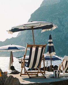 chairs and umbrellas on the beach with mountains in the backgroung area