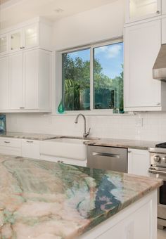 a kitchen with marble counter tops and white cabinets