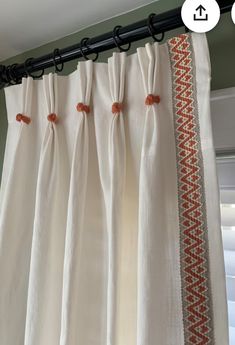 an image of curtains with orange trims hanging on the curtain rod in front of a window