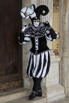 a man dressed as a clown standing in front of a building